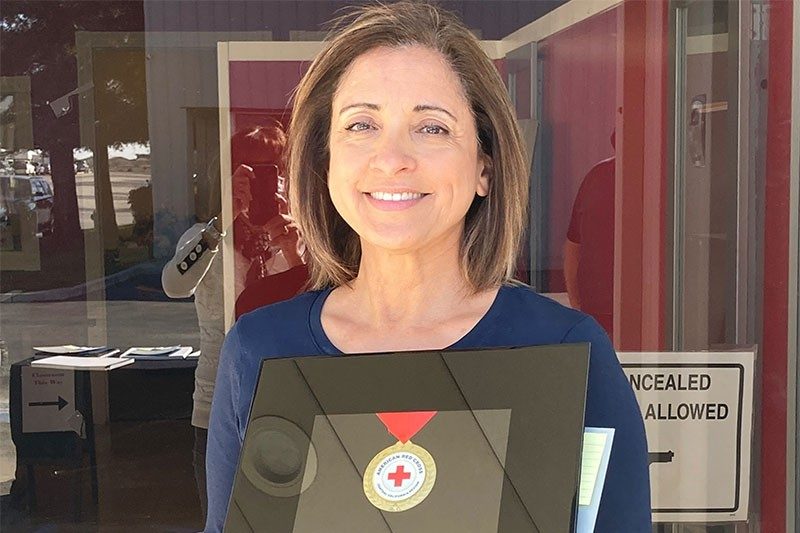 Christine Wilson sniling holding Red Cross award.