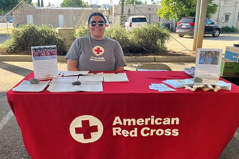 Diana Manzo-Prado sitting at American Red Cross display table.