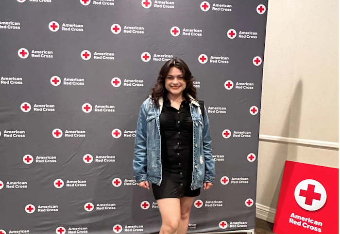 Janessa Paez standing in front of Red Cross logo backdrop.
