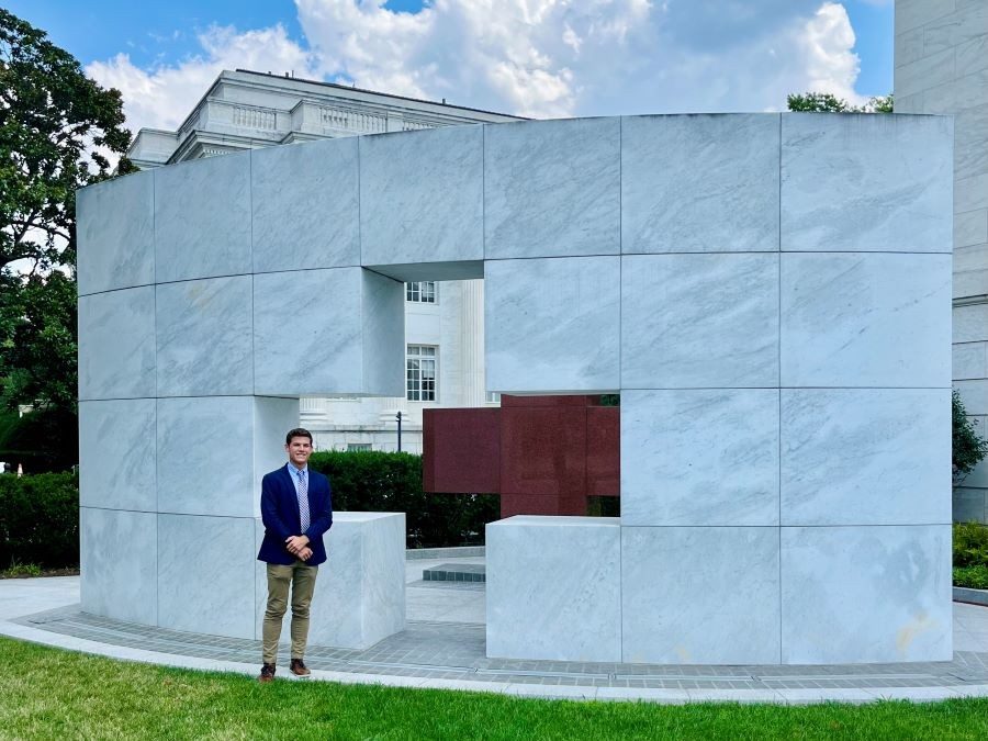 person in a suit smiling in front of a building