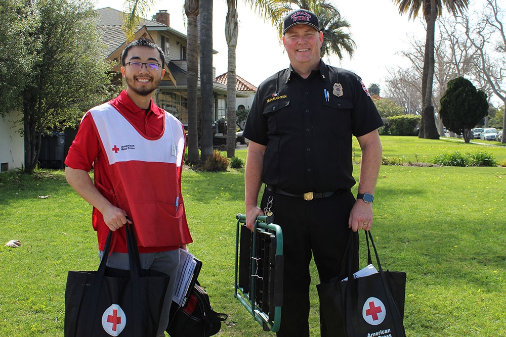Red Cross volunteer and a Oxnard fire fighter holding equipment to install smoke alarms.
