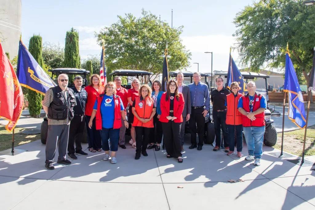 Group photo of Red Crossers standing in front of golf carts and flags