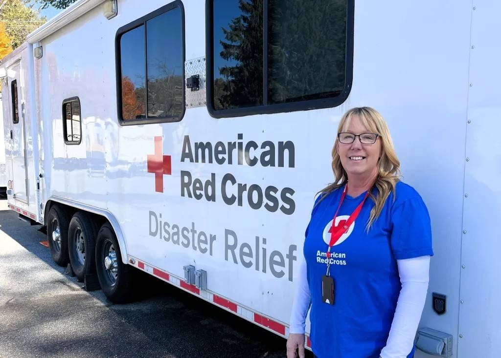 Woman stands in front of Red Cross vehicle