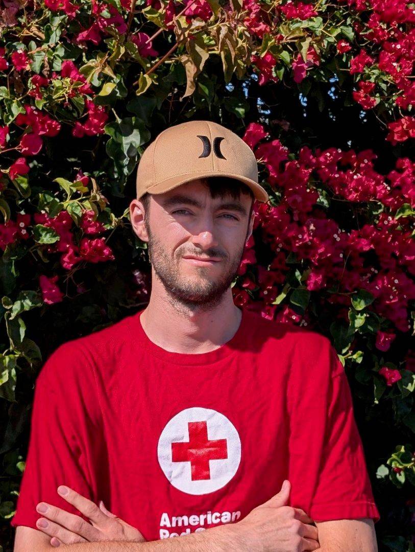 Young man in Red Cross shirt stands outside
