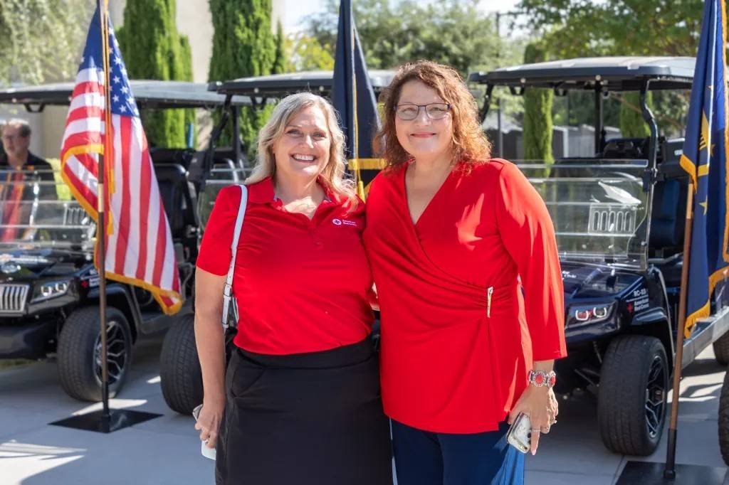 Two women stand in front of golf carts