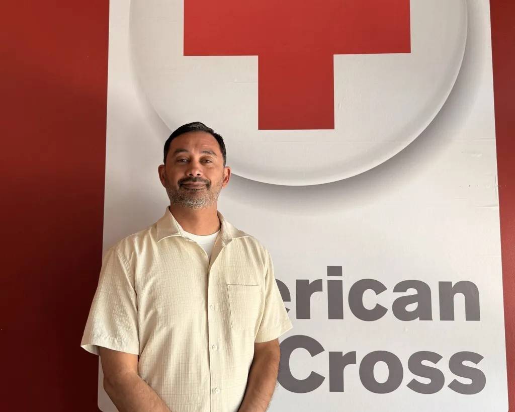 Man stands in front of Red Cross logo