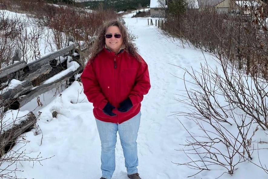 Woman in red jacket stands on snowy path