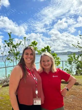 two women stand in front of ocean
