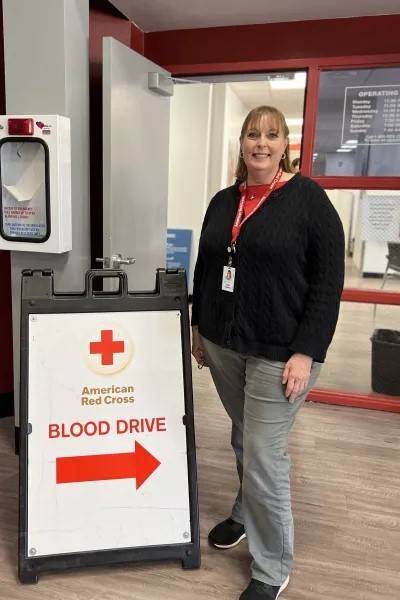 Woman stands by Red Cross blood drive sign