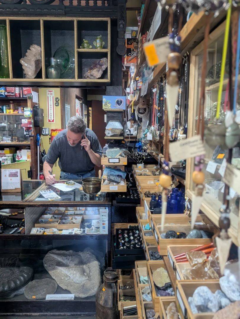Man talks on the phone while taking notes at front desk of store