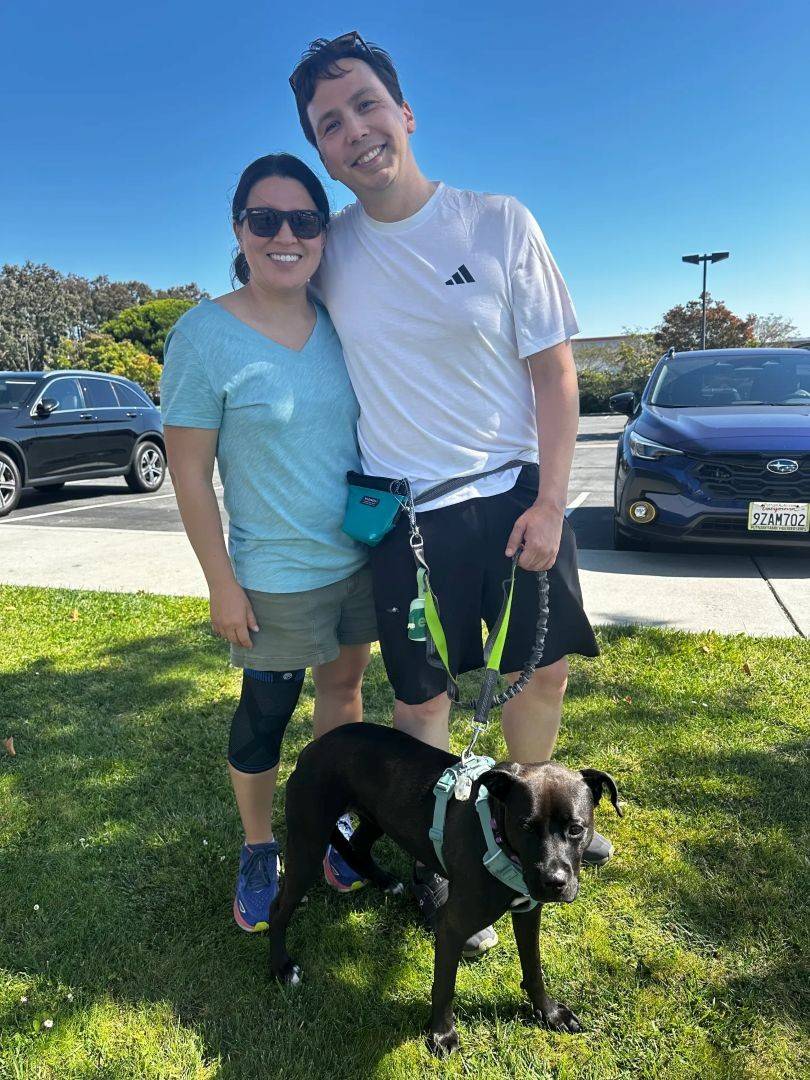 Man and woman stand with dog at their feet
