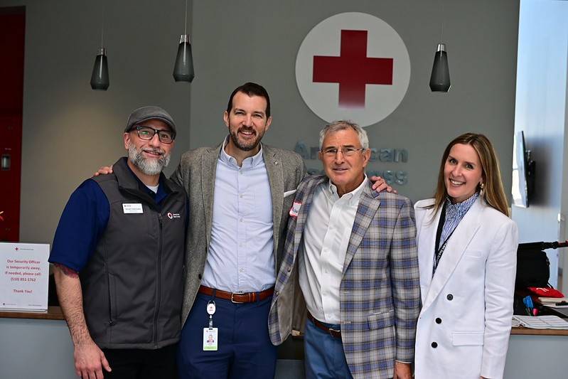Group photo of four people in front of Red Cross logo