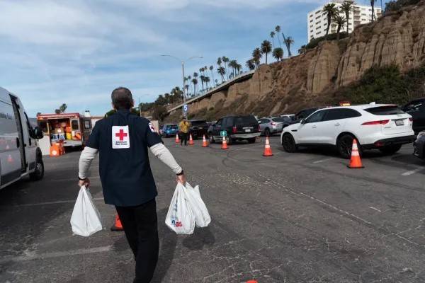 Red Cross volunteer carries bags of relief items to cars