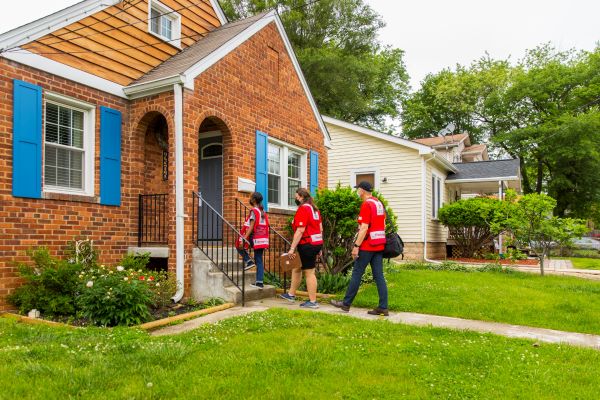 three red cross volunteers walking up to a home