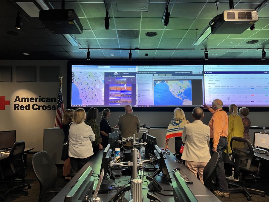 a group of people looking at a screen in a red cross office