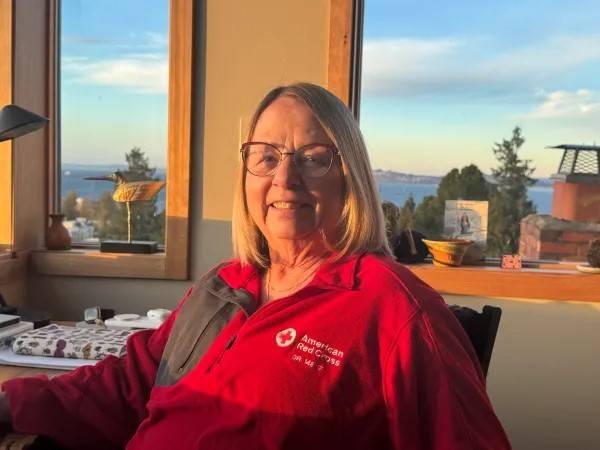 Woman in Red Cross jacket sits at desk