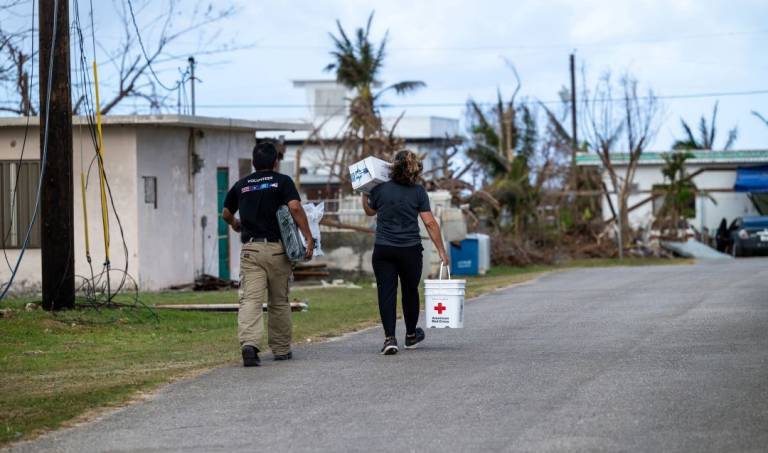 Two people carry relief supplies down the street