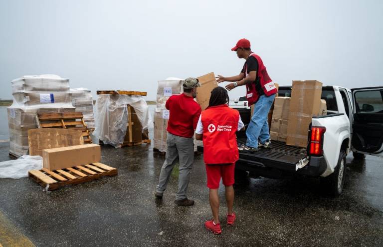 Red Cross volunteers load equipment and supplies into trucks