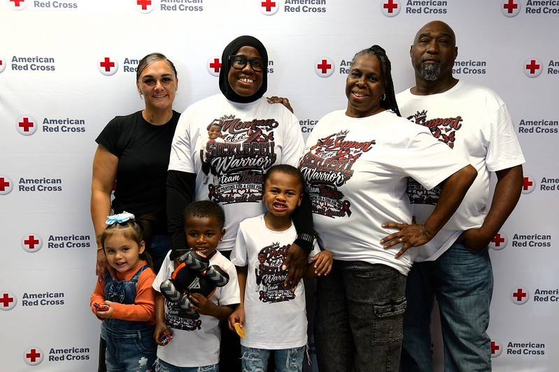 Group of people stand in front of Red Cross backdrop