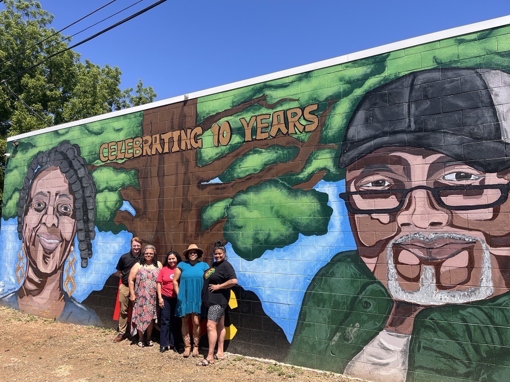 Group of people standing in front of a wall mural