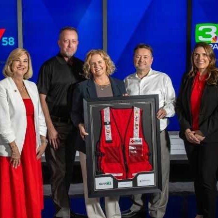 people stand in newsroom with red cross award