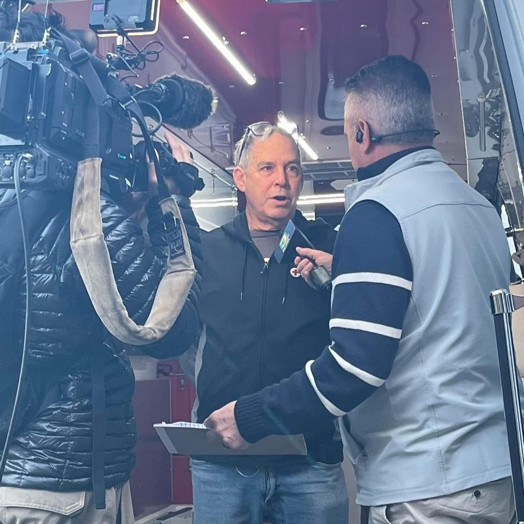 two men talk with tv camera nearby