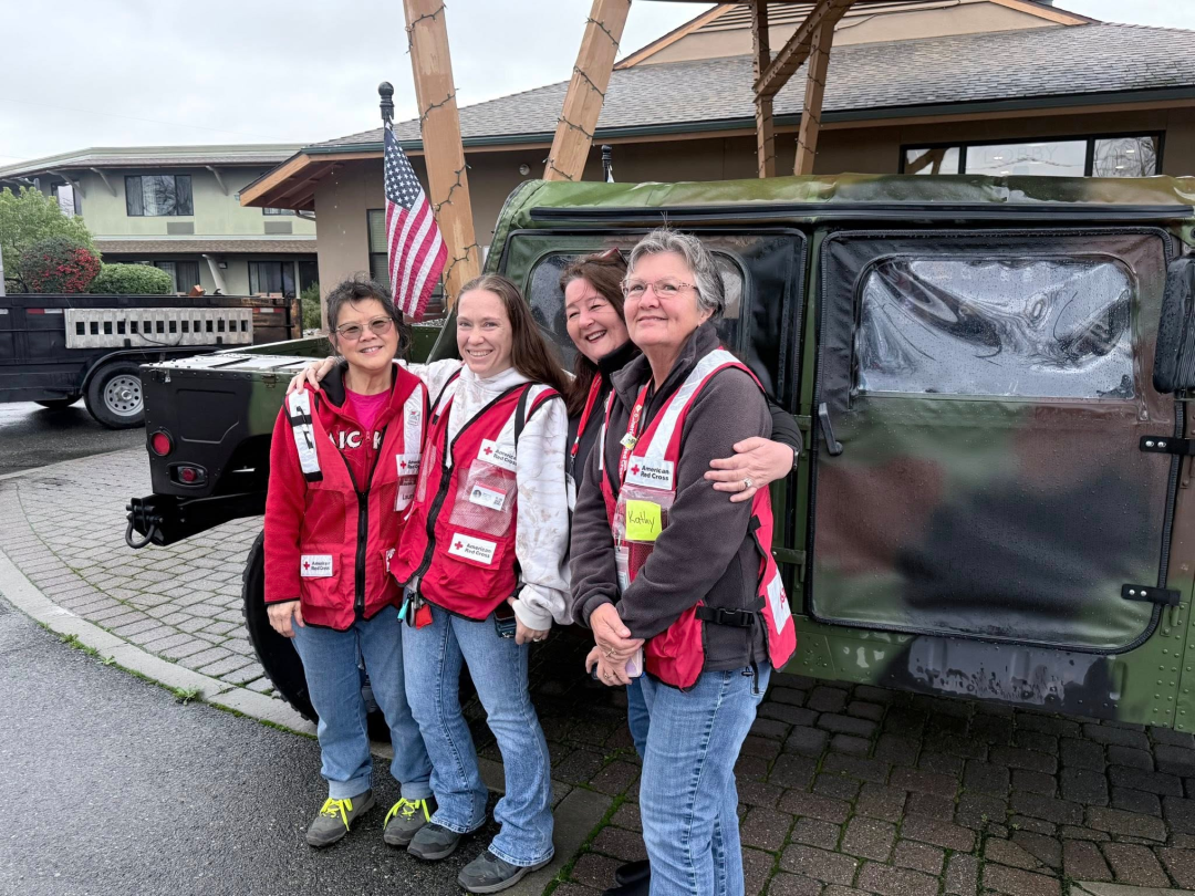 Four Red Cross volunteers stand in front of truck
