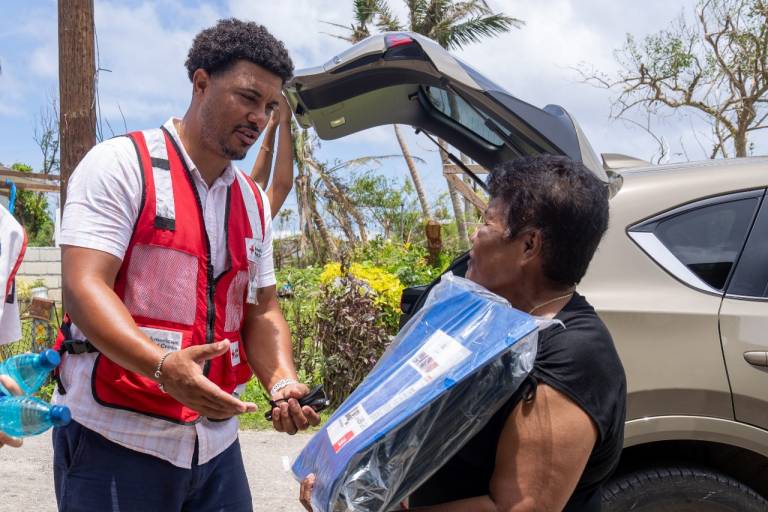 Red Cross volunteer unloads items from trunk of car