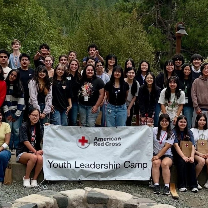group of youth stand behind red cross banner