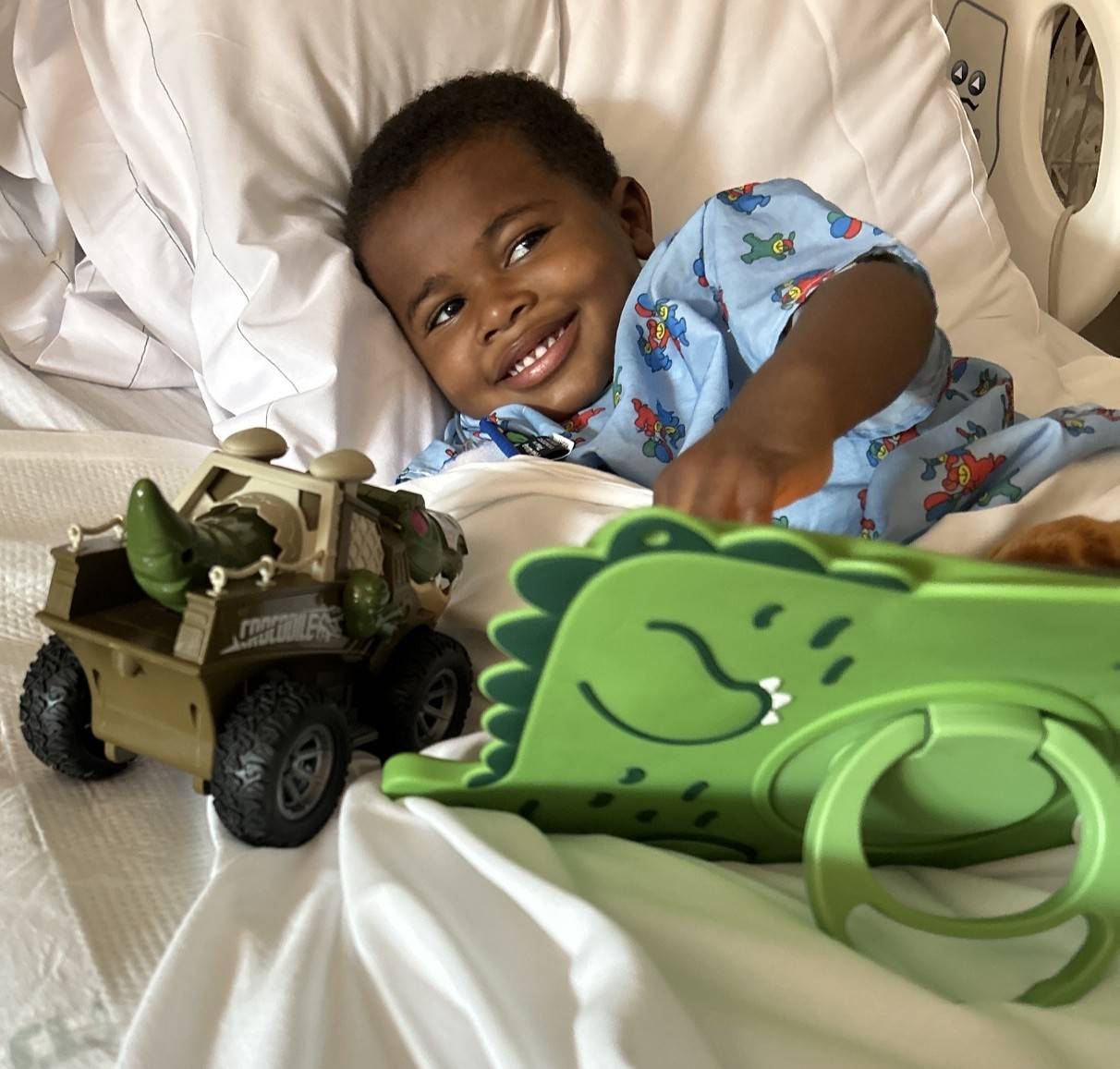 Isiah Harris plays with toys in hospital bed