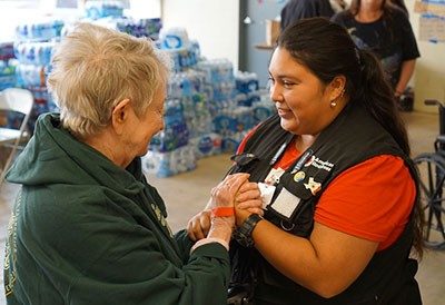Red Cross volunteer holding hands with older woman