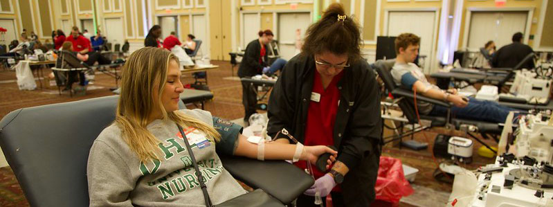 People sitting in cots donating blood