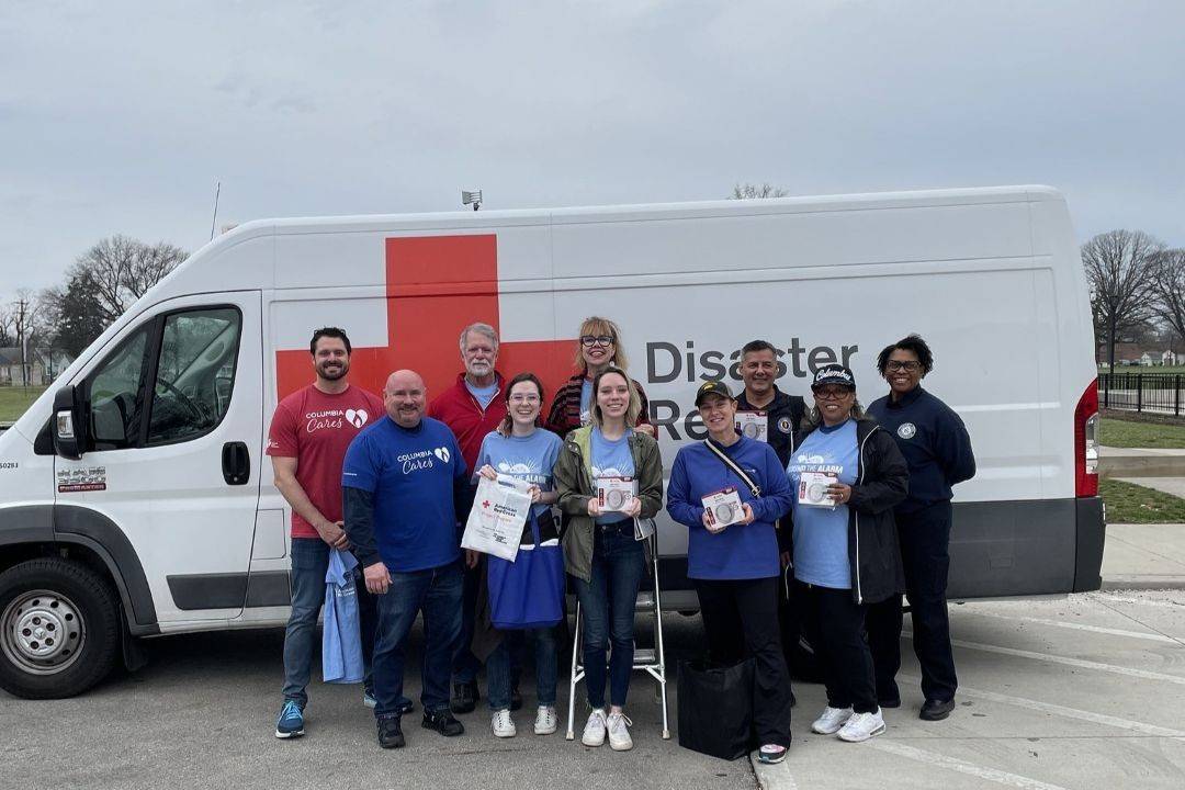 Group of Red Cross volunteers stand in front of Red Cross vehicle