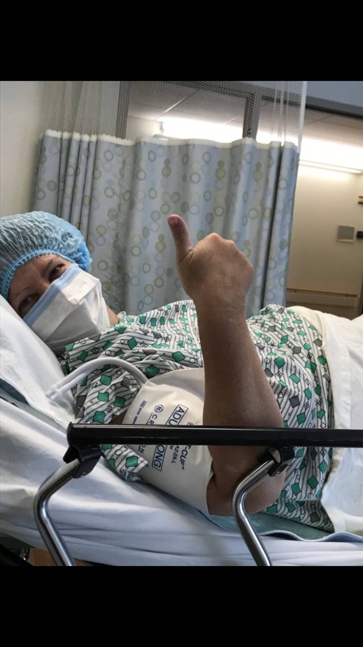 Susan Hoskinson laying in hospital bed wearing a mask.