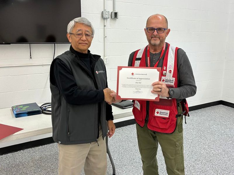 red crosser holding award and shaking hands