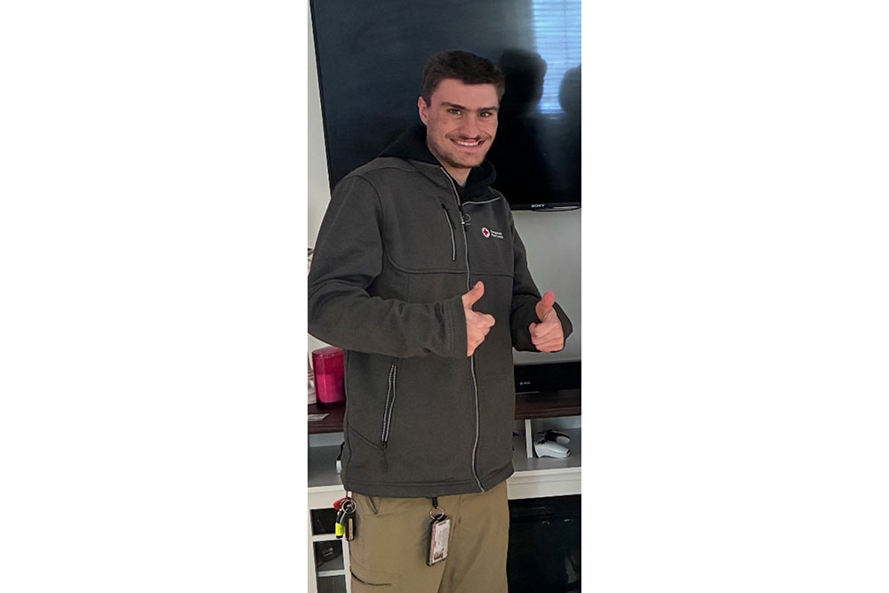 Alex Kuczenski wearing a Red Cross jacket and giving a thumbs up.