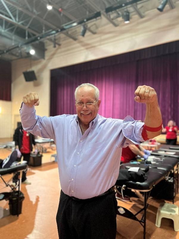 Man holds hands overhead in victory pose after donating blood
