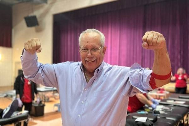 Man holds arms in strong arm pose after donating blood