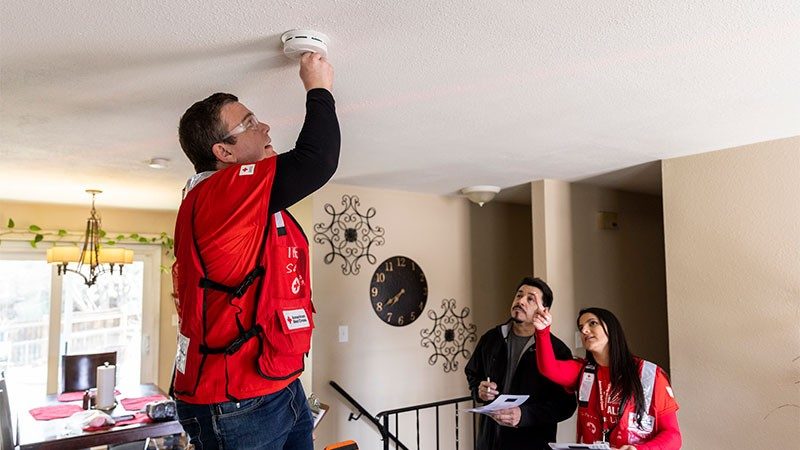 Red Cross volunteer installing smoke alarm in house