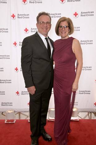 Man and Woman stand in front of Red Cross backdrop