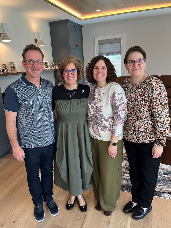 Jessica stands with her two sisters and husband inside her home