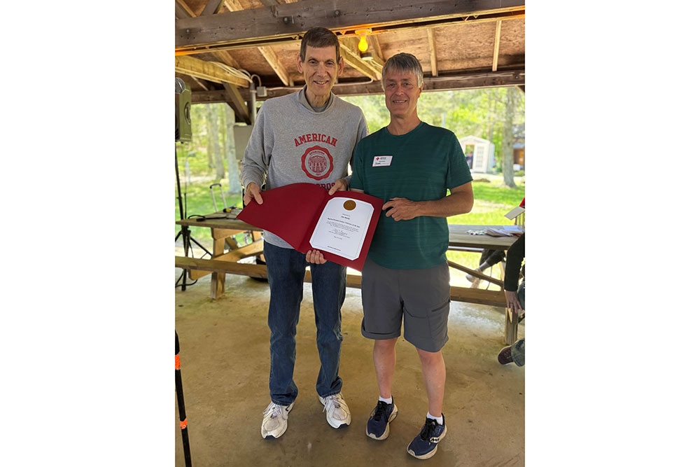 Jim Murdy and a Red Cross staff member displaying a Red Cross award.
