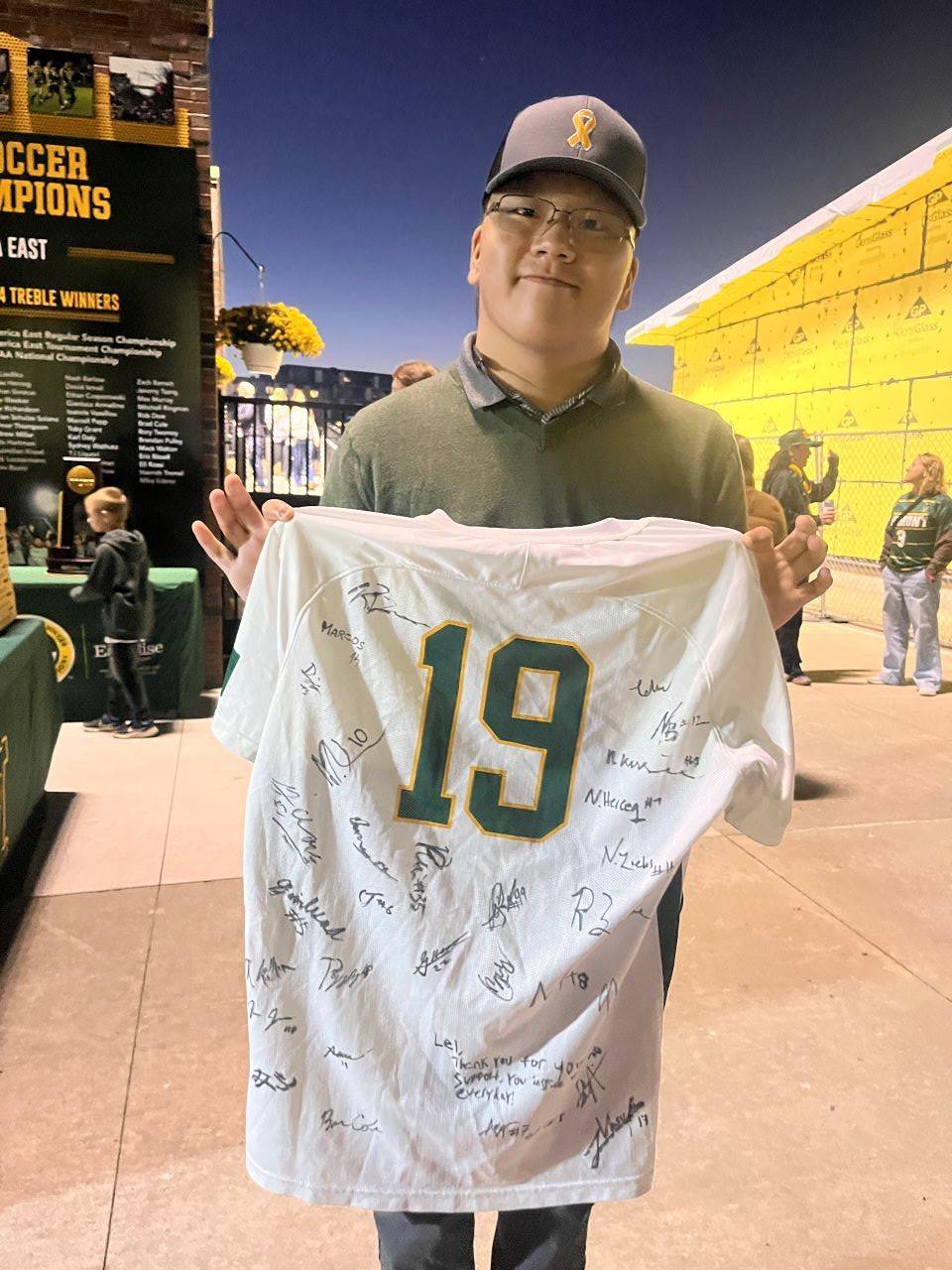 Young man holds up tshirt signed by teammates