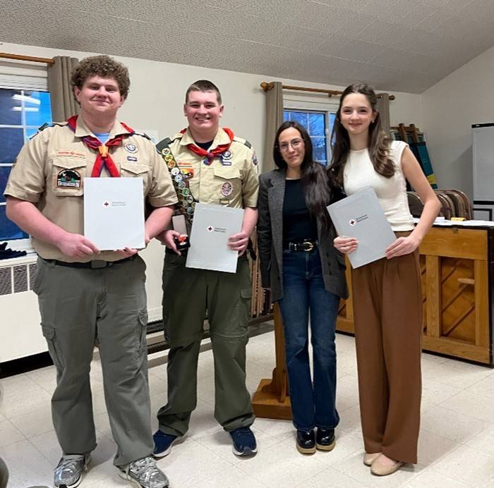 Two men and two women stand holding Red Cross awards