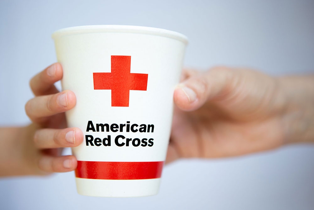two hands holing an american Red Cross paper cup.