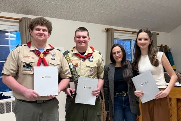 Two women and two men stand holding awards