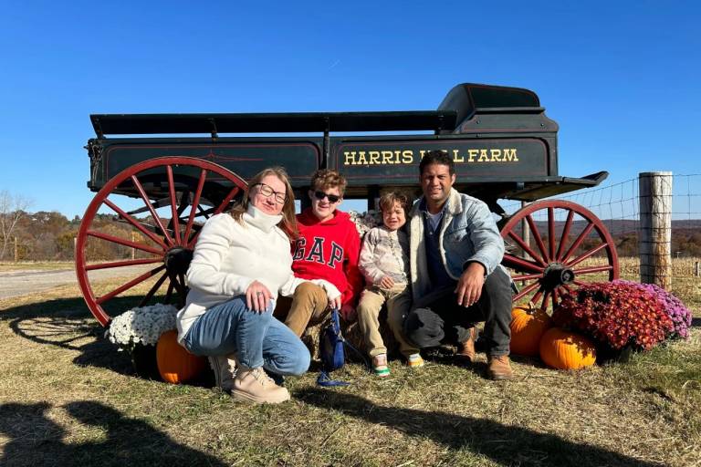 family sitting in front of hay wagon