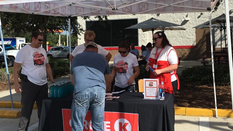 Red Cross volunteers and person at outdoor Red Cross booth