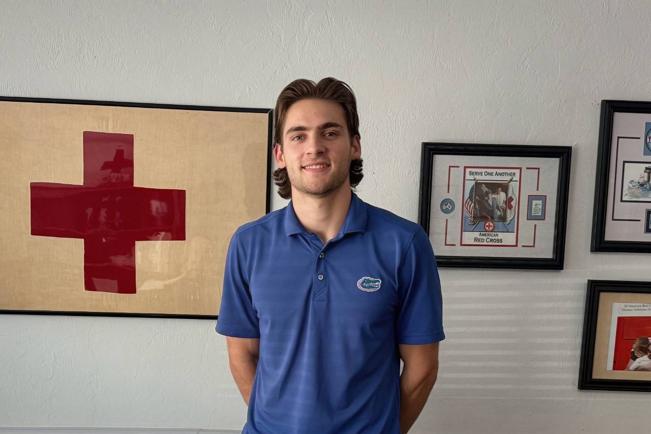 Man in blue polo stands in front of wall with Red Cross decor