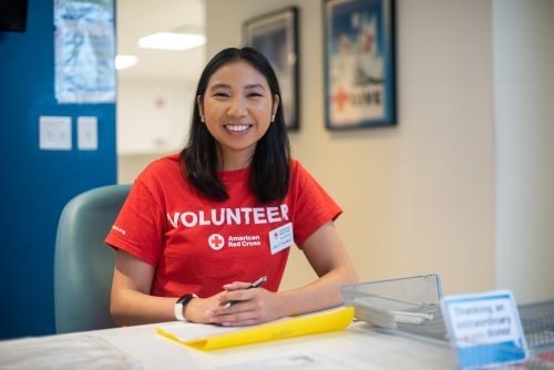 red cross volunteer smiling sitting at desk
